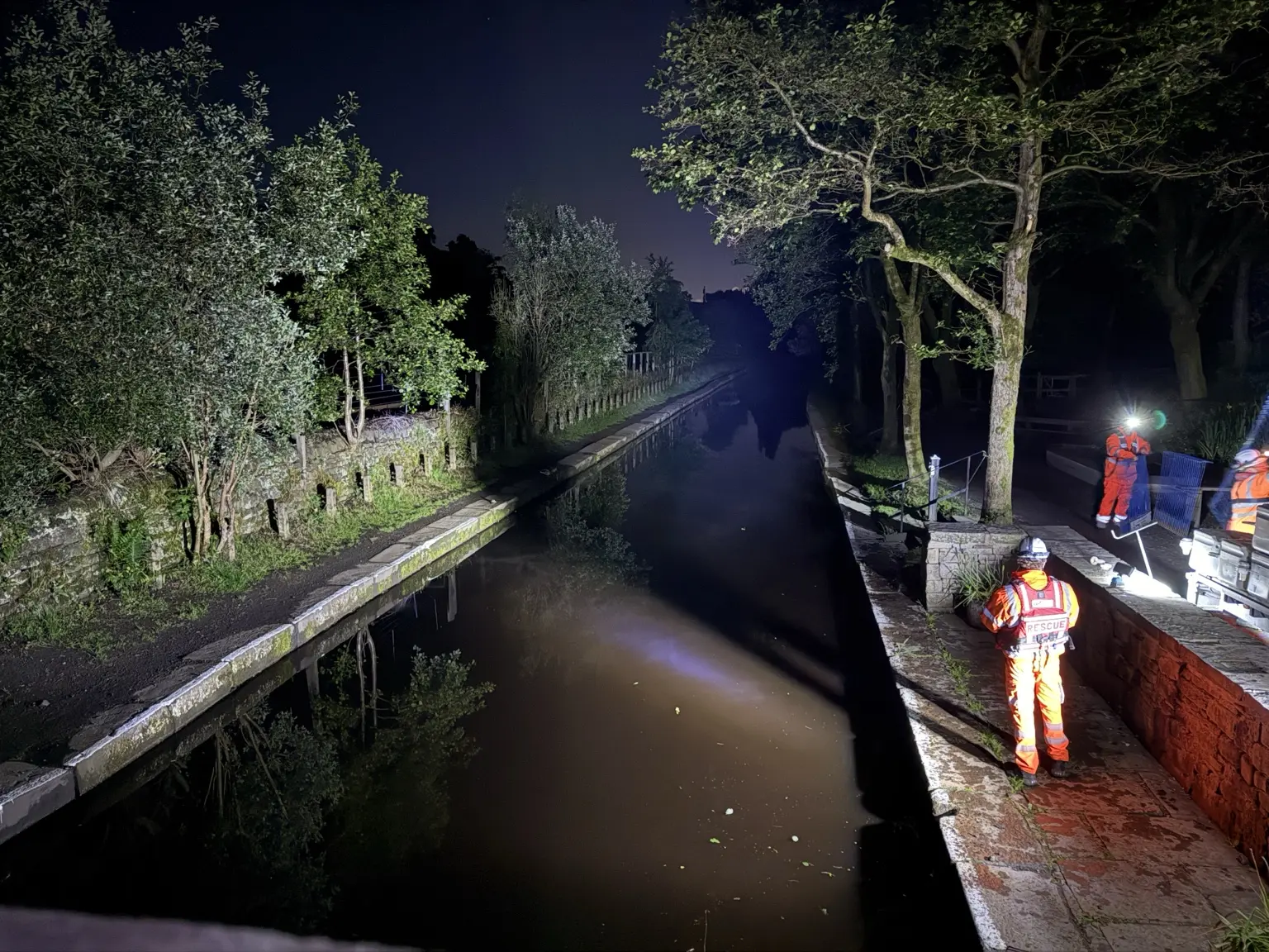 Water rescue and specialist support beside a canal at night