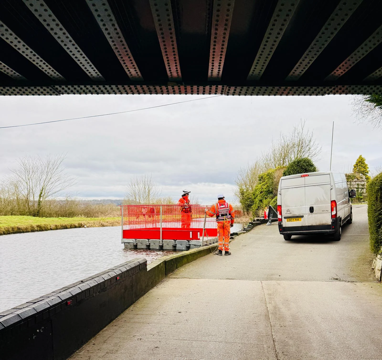 Operatives working beside a bridge and watercourse