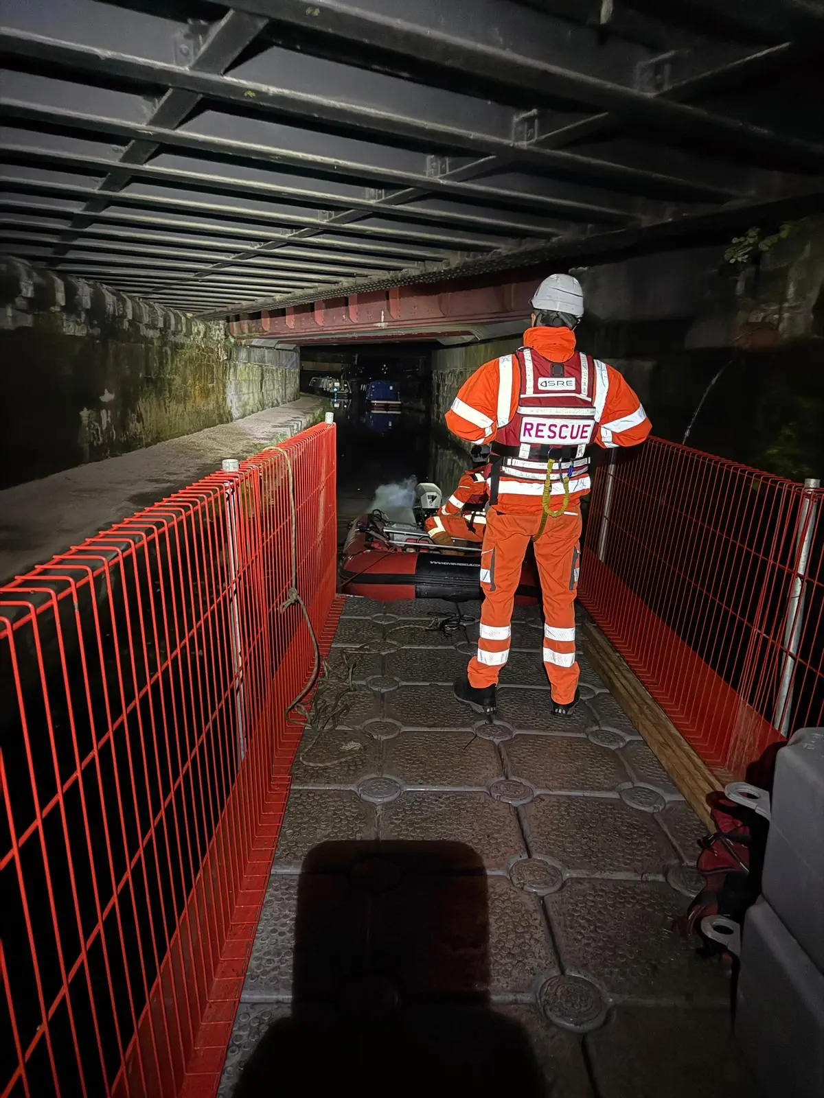 Rescue operative standing on a protected floating walkway beneath a bridge